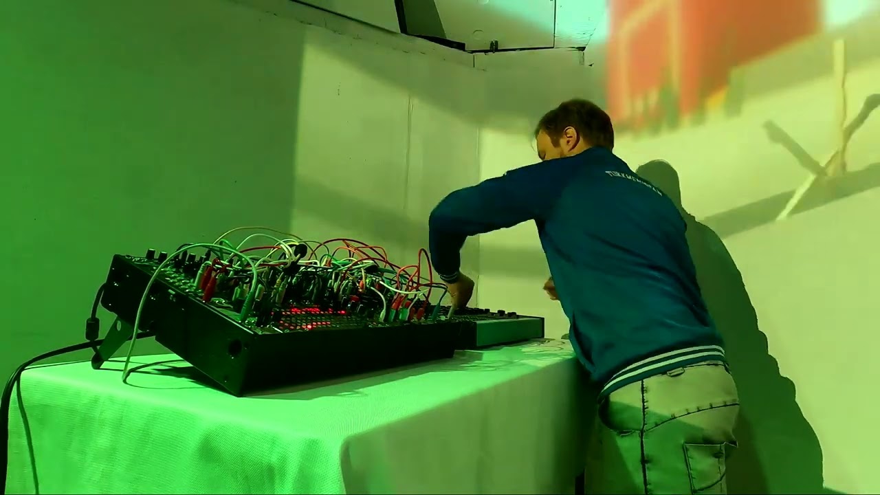 Performer at a modular synthesizer on a table in green light